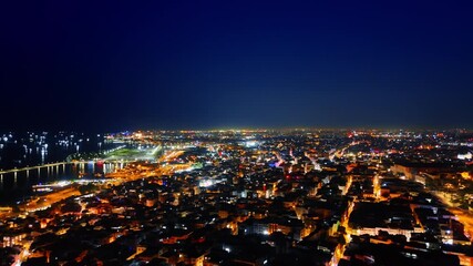 Glowing cityscape of the beautiful city at night. Illuminated shore and yachts on the waterscape. Kemer, Turkey from top view.