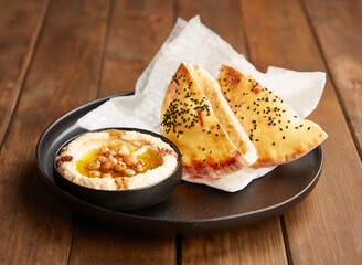 Homemade Pita Bread with Creamy Hummus, Tahini Sauce, Chickpeas and Olive Oil in plate side view of Mediterranean cuisine