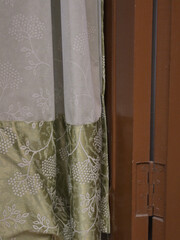 Sheer white and olive green curtains feature a delicate vine and leaf pattern, adding a decorative touch.