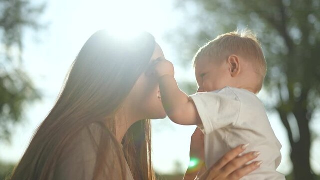 Happy mother holding baby park. Mother gently embraces happy baby outdoors. Joyful bonding moment between mother and baby park. Emotional connection in sunlight. Happy mother enjoying time baby park.