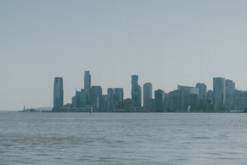 Fototapeta premium City skyline showcases modern architecture along the waterfront during a clear day with minimal clouds. The view of the Jersey side of the Hudson River from New York. side