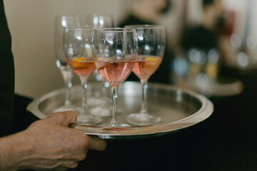 Waiter serves refreshing cocktails on a silver tray at upscale event venue during evening gathering