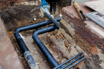 New modern insulated urban pipeline installation construction site  exposed underground pipes in shored trenches. Insulated steel pipes lie connection engineering infrastructure upgrade work