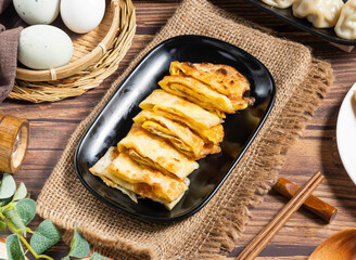 Golden Egg Pancake Rolls on a Black Plate, Asian Breakfast side view of hong kong food