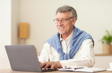 Happy Senior Man Working On Laptop Computer Sitting In Modern Office. No Ageism Concept. Selective Focus