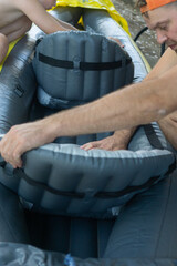 Father and son assembling grey inflatable boat, two males setting up rubber raft for water...