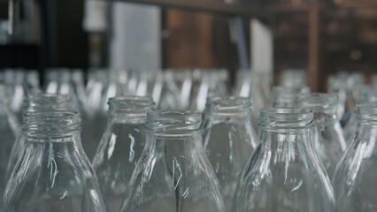 Empty glass bottles passing on conveyor belt in
