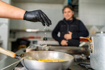 Chef sprinkling cheese into seafood dish in restaurant kitchen