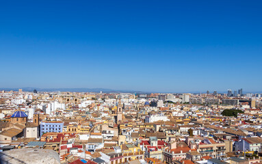 Fototapeta premium Panoramic view of Valencia showcasing its diverse architecture under a clear blue sky. The vibrant cityscape features historic and modern buildings, capturing the essence of urban life.