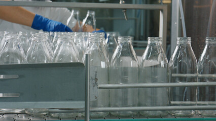 Empty glass bottles moving on conveyor belt in