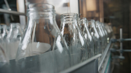 Empty glass bottles moving on conveyor belt in
