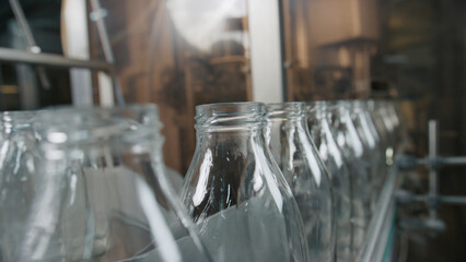 Empty glass bottles moving on conveyor belt in