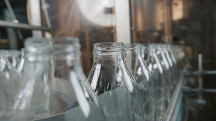 Empty glass bottles moving on conveyor belt in