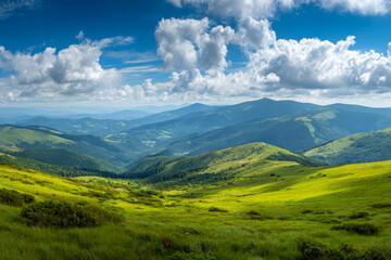 Obraz premium Scenic view of lush green rolling hills and distant mountains under a bright blue sky with scattered clouds