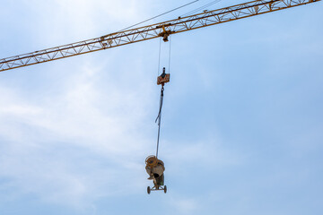 Crane lifting construction equipment against a clear blue sky, showcasing industrial machinery in...