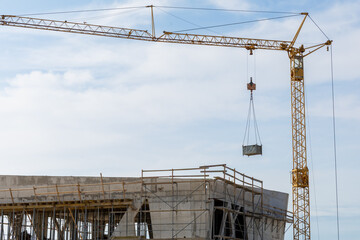Construction crane lifting materials at a building site under a clear blue sky, showcasing modern...