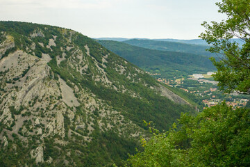 Fototapeta premium Mountains in trieste area italy, green hilly landscape with rocky slopes and distant town, scenic view of italian countryside, concept of travel destination, tourism, landscape photography