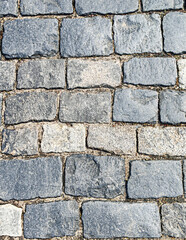 Textured cobblestone pavement featuring various shades of gray stones arranged in a classic pattern, showcasing the durability and aesthetic appeal of traditional street surfaces