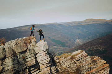 Hikers helping each other on mountain peak reaching for success