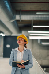 Female engineer inspecting building while taking notes in her notebook