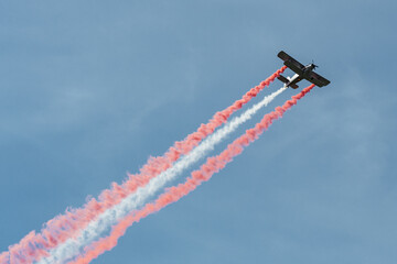 Old model of military aircraft performing in the sky emitting smoke in the colors of the Latvian...