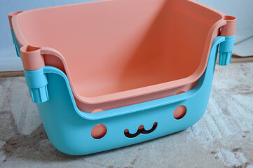 stacked colorful plastic storage baskets with cute cartoon-like face cutouts, featuring pastel...