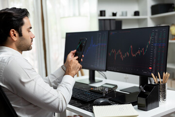 Trader businessman searching on smartphone, analyzing in dynamic stock exchange investment screen on pc with invest highest profitable financial technology market at modern home office. Surmise.