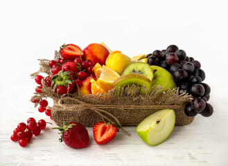Fresh summer berries and fruits in a rustic basket on the table. Healthy foods, healthy nutrition. Currants, grapes, apples, apricots and strawberries are prepared for breakfast