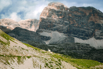 Small White Chapel on Grassy Hill Beneath Rocky Cliffs in Tre Cime di Lavaredo, Italy