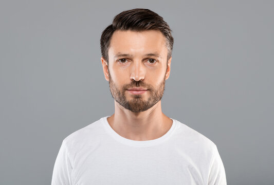 Portrait of handsome bearded man over grey studio background, empty space. Middle-aged bearded man posing for male magazine or blog, youth, healthy lifestyle and male cosmetology concept