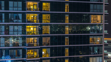 Glowing apartment windows at night in glass skyscraper timelapse