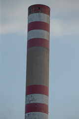 A beautifully designed red and white striped chimney stands prominently against a backdrop of a cloudy sky filled with various shades of gray