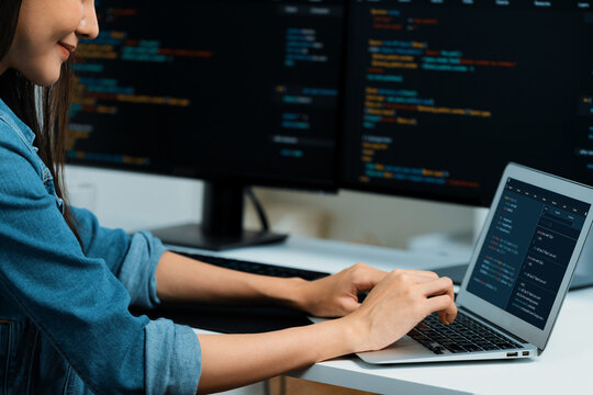 Smiling young Asian in IT developer creating with typing online information on laptop with coding program data of application, wearing jeans shirt. surrounded by safety analysis two screen. Stratagem. - Powered by Adobe