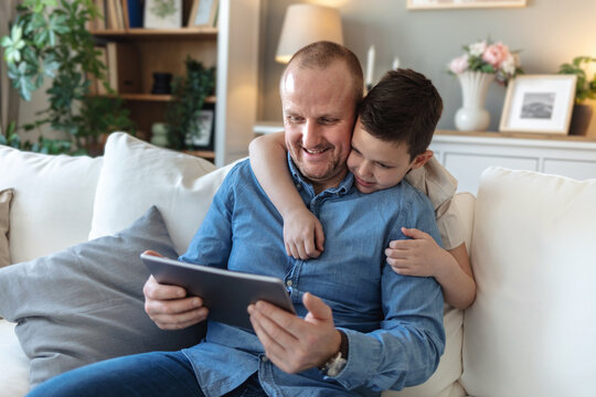 Home, dad and boy with laptop for video call on sofa in living room for communication and networking. People, parent and kid with smile or happy on couch in lounge with wave, fun and bonding.