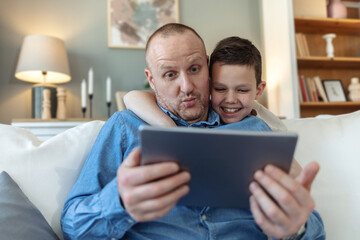 Happy, tablet and father with child in home for watching movies, cartoons and online entertainment. Family, love and dad with son on digital tech for internet, video call and relax on weekend on sofa.