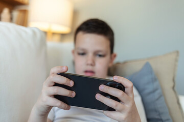 Couch, boy with phone for games, movies or streaming cartoon weekend in home. Entertainment, relax or kid gaming on sofa with mobile connection for video, playing online or addiction.