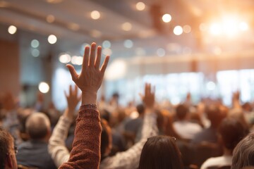 Audience raising hands in a conference hall with warm lighting