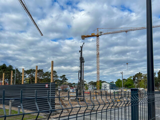 A construction site of an apartment building on the Baltic Sea in Mrzezyno, Poland with a crane and a machine for drilling holes in the ground (a huge drill)