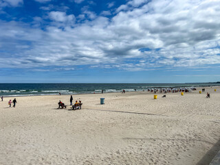 An almost empty beach near the entrance to the pier in Kolobrzeg on the Baltic Sea in Poland in early May on a sunny day