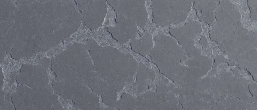 Natural cracked soapstone with intricate light vein structure on dark gray surface