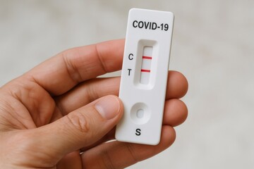 Close up image capturing a hand holding a positive COVID 19 antigen rapid diagnostic test cassette, highlighting the importance of quick diagnosis