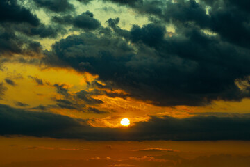 Dark dramatic horizon sky during sunset. Black clouds and setting sun