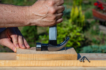 A worker using a hammer nail puller to pull a nail out of a wooden board, closeup. Hand tool for...