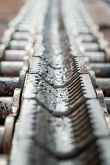 Close-up at surface on gripper chain of the conveyor machinery part. Industrial equipment object.