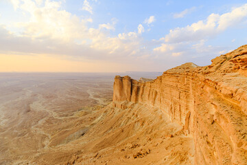 Dramatic cliffs of Tuwaiq mountain range at sunset creating breathtaking view over vast desert landscape near Riyadh, Saudi Arabia, showcasing beauty and tranquility of nature