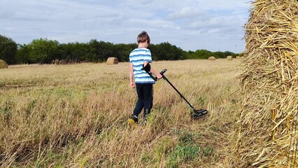 guy with a metal detector is looking for a treasure against the background of the field. teenage boy with a metal detector in his hands in search of treasure