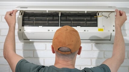 Man open dusty filters in conditioner. A man open the lid of broken air conditioner to control the filters inside