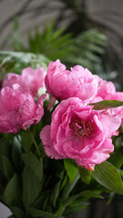 bouquet of pink peonies and green leaves in a vase close-up