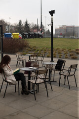 A woman is sitting at a lovely table outdoors in a nice setting, deeply engaged in reading an interesting book