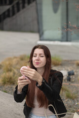 Fototapeta premium A woman with long black hair is sitting comfortably on a bench, intently looking at her phone while enjoying the winter day